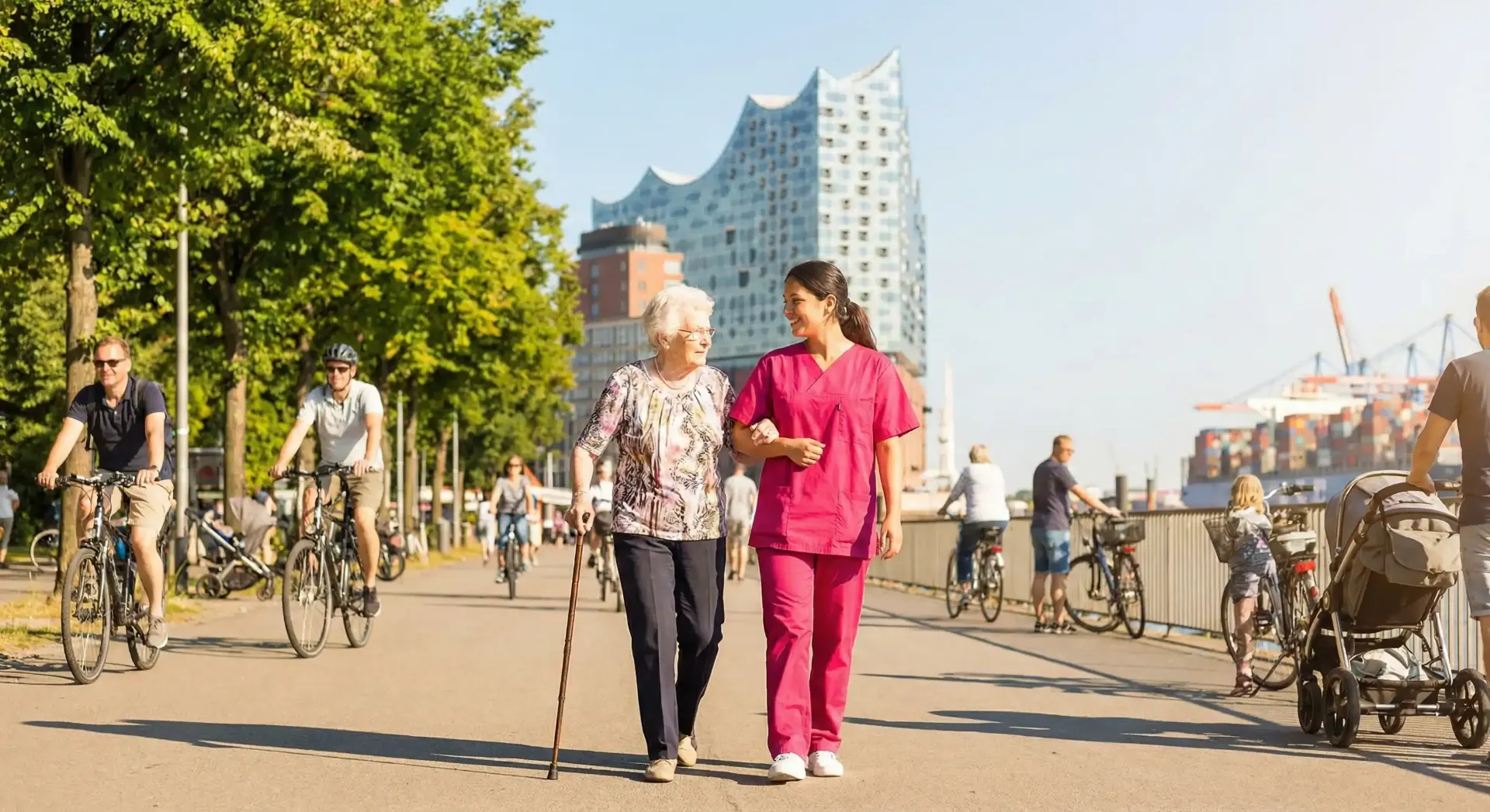 Mitarbeiterin des Pflegedienstes spaziert mit der Patientin in Hamburg